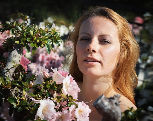 Schönheits- und Jugendkonzept. Porträt einer schönen blonden jungen Frau unter den Blumen der Azalee