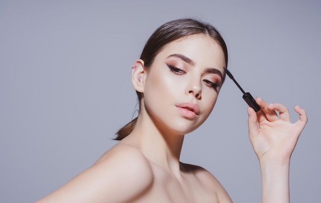 Schönheits- und Kosmetikfrau, die schwarze Mascara auf Wimpern perfektes Make-up setzt