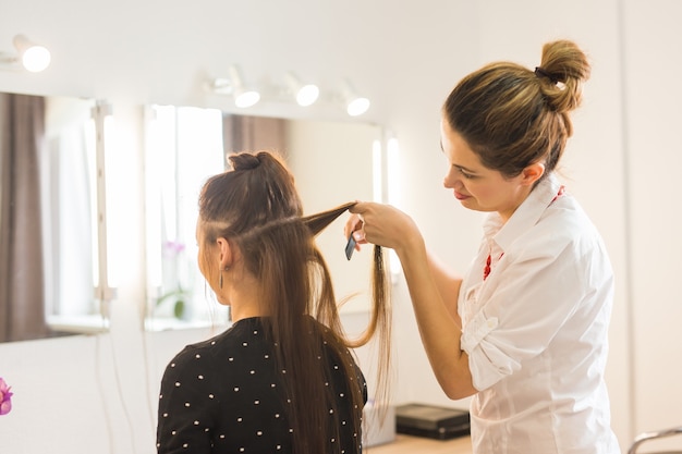 Schönheits- und Menschenkonzept - glückliche junge Frau mit Friseur im Friseursalon.