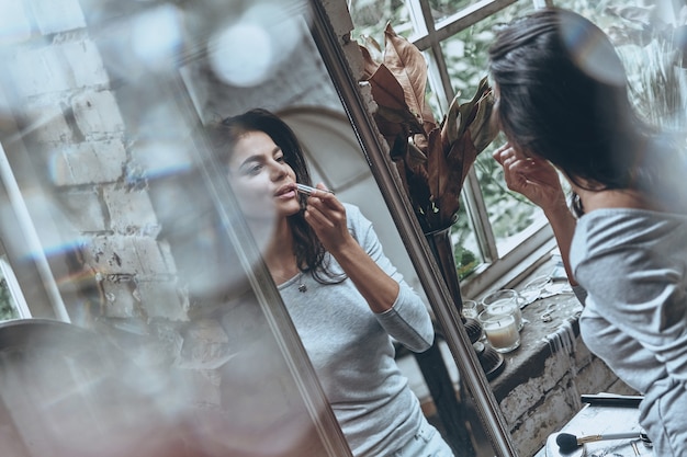 Schönheitsbehandlung. Attraktive junge Frau, die etwas Make-up aufträgt