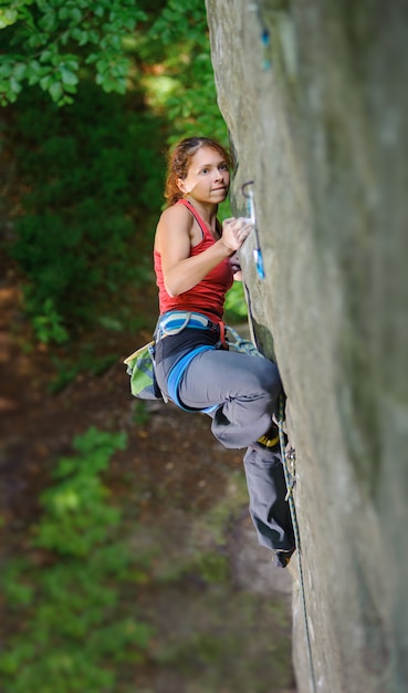 Schönheitsbergsteiger, der steilen Felsen mit Seil klettert