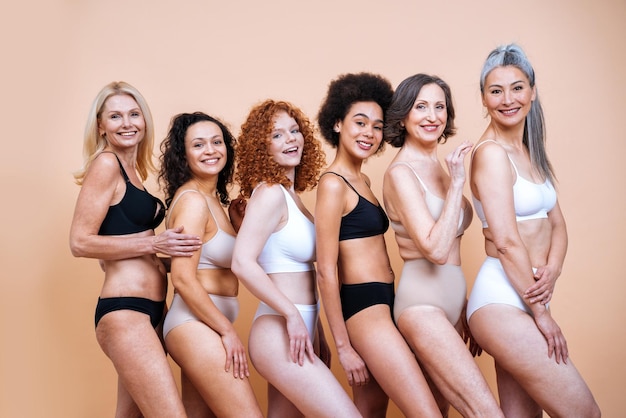 Schönheitsbild einer Gruppe von Frauen mit unterschiedlichem Alter, Haut und Körper, die im Studio für ein körperpositives Fotoshooting posieren. Gemischte weibliche Models in Dessous auf farbigen Hintergründen