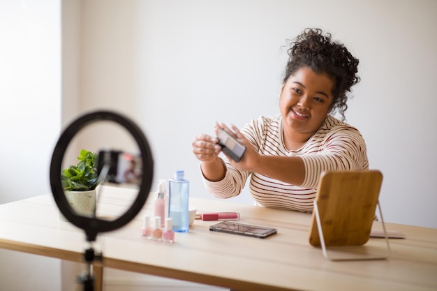 Schönheitsbloggerin mit Make-up-Produktaufzeichnungsvideo auf dem Smartphone