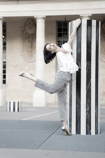 Schönheitsfrauenhaltung in Paris, Frankreich. Beauty Model Pose in Schuhen mit hohen Absätzen an der Spalte.