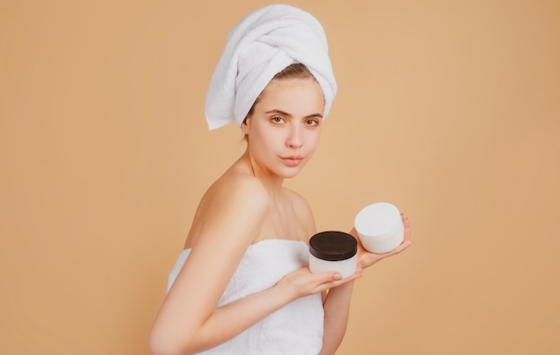 Schönheitsgesichtsporträt Cremeflasche Badekurorttherapie schöne Frau im Handtuch kümmert sich um Hautgesten f
