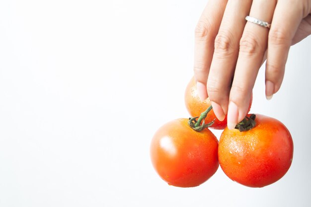 Schönheitshand mit Tomaten auf weißem Hintergrund