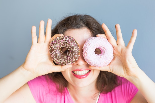 Schönheitsmädchen, das bunte Donuts nimmt. Lustige fröhliche Frau mit Süßigkeiten, Dessert. Diät, Diätkonzept. Junkfood, Feiern und Party.