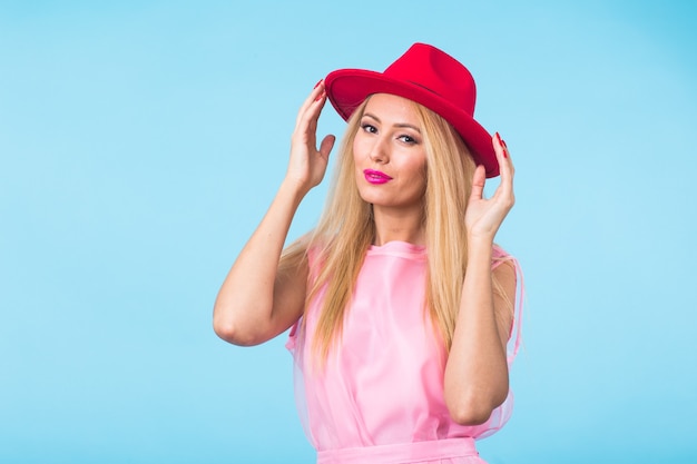 Schönheitsmode-Sommerporträt der blonden Frau mit roten Lippen und rosa Kleid auf blauer Wand mit