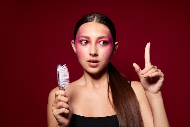 Schönheitsmode weibliches rosafarbenes Gesichtsmake-up, das attraktiven Blick mit einem Kammrosahintergrund unverändert aufwirft