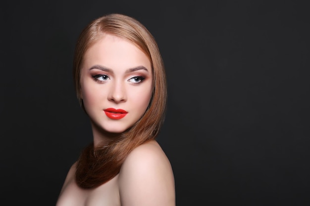 Schönheitsmodell auf schwarzem Hintergrund, Modeschießen. Frau mit Make-up, perfekter Haut und Haaren posiert vor der Kamera im Studio, Kopierraum
