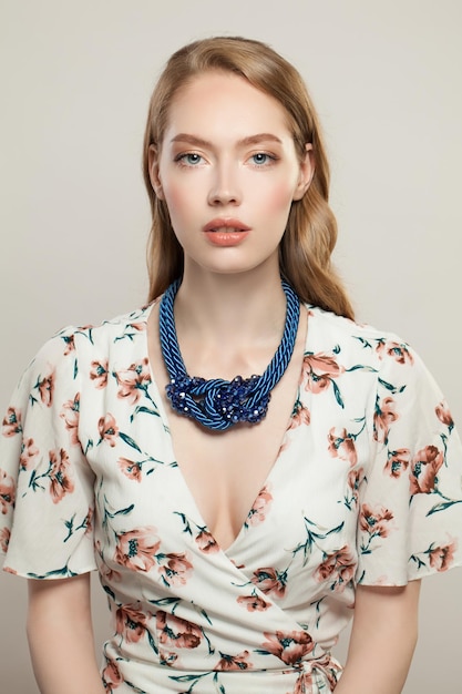 Schönheitsmodell mit dem langen Haar des natürlichen Make-ups und blauer Halskette auf weißem Hintergrund