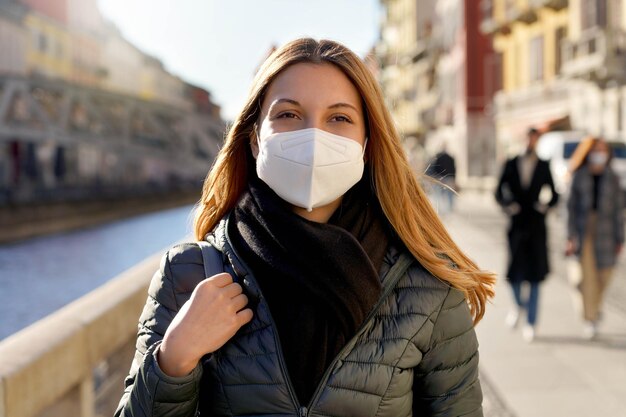 Schönheitsmodemädchen, das eine schützende Gesichtsmaske trägt, die bei Sonnenuntergang auf der Straße der Stadt spazieren geht