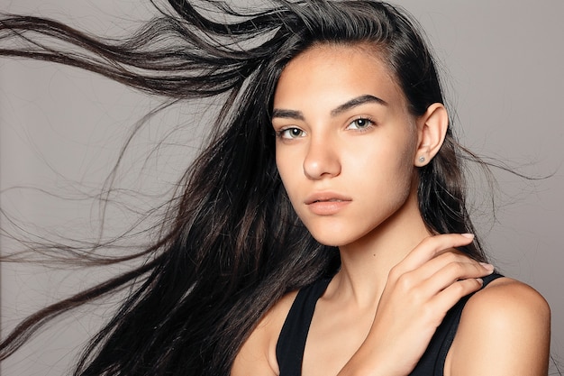 Schönheitsmodeporträt des jungen schönen Brunettemädchens mit dem langen schwarzen geraden fliegenden Haar. Herrliches Haar. Rauchige Augen. Vogue-Stil.