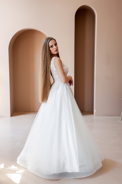 Schönheitsporträt der Braut, die Modehochzeitskleid mit Federn mit luxuriösem Freudenmake-up trägt