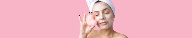 Schönheitsporträt der Frau in weißem Handtuch auf dem Kopf trägt Creme auf das Gesicht auf Hautpflege-Reinigung Öko-Bio-Kosmetik-Spa-Relax-Konzept