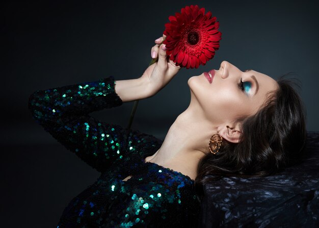 Schönheitsporträt einer Frau mit schönem Abendmake-up und Blumen auf ihrem Gesicht