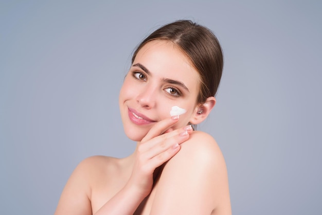Schönheitsporträt einer schönen Frau, die Gesichtscreme aufträgt Frau, die feuchtigkeitsspendende Hautpflegecreme, Lotion oder Maske für Hautlifting und Anti-Aging-Effekt aufträgt Studio-Hintergrund