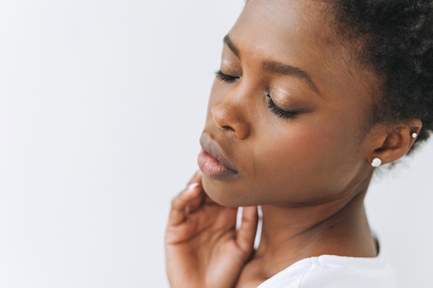 Schönheitsporträt schöner junger afroamerikanischer Frauenhände in der Nähe von Gesicht auf weißem Hintergrund