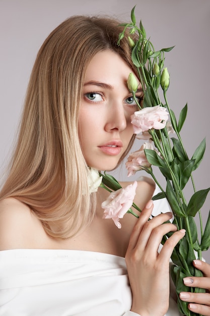 Schönheitsporträtfrau mit rosa Eustoma-Blumen in ihren Händen.