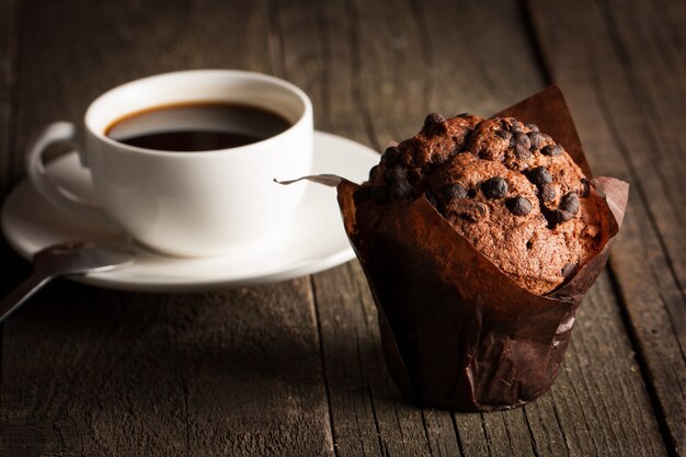 Schokolade dunkel gekochtes Muffin mit Minze auf einem Holztisch mit Zimt, Anis, Schokolade.