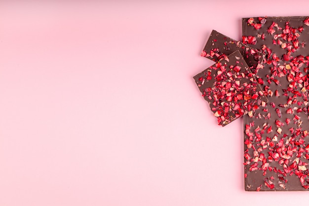 Schokolade mit Stücken getrockneten Erdbeeren liegt ein Stapel auf rosa Hintergrund