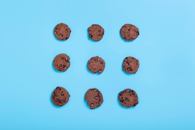 Schokolade und weiße Kekse auf blauem Grund. Ansicht von oben, flach.