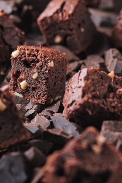 Schokolade wird auf Brownie mit Nüssen gegossen Süße und leckere Dessertnahaufnahme auf einem Holztisch