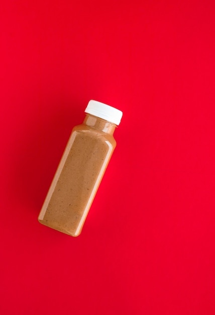 Foto schokoladen-bananen-smoothie-flasche auf rotem flatlay