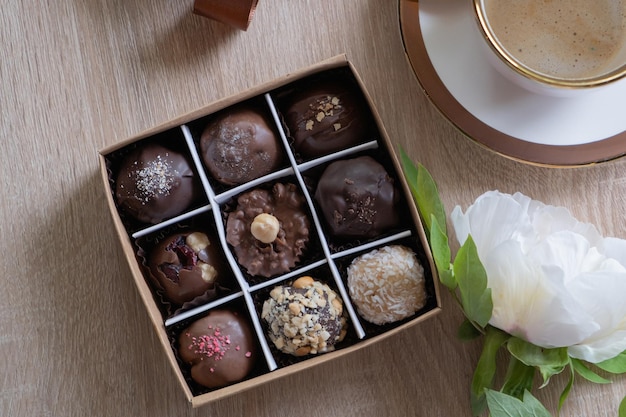 Schokoladen-Bastelbonbons in Schachtel mit Kaffee und Blumen auf der Tischplatte, flach liegend
