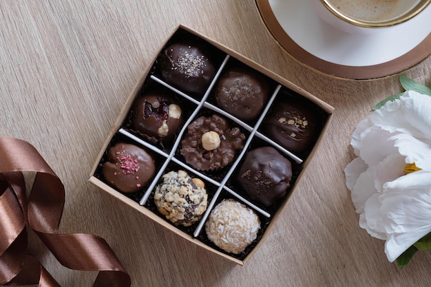 Schokoladen-Bastelbonbons in Schachtel mit Kaffee und Blumen auf der Tischplatte, flach liegend