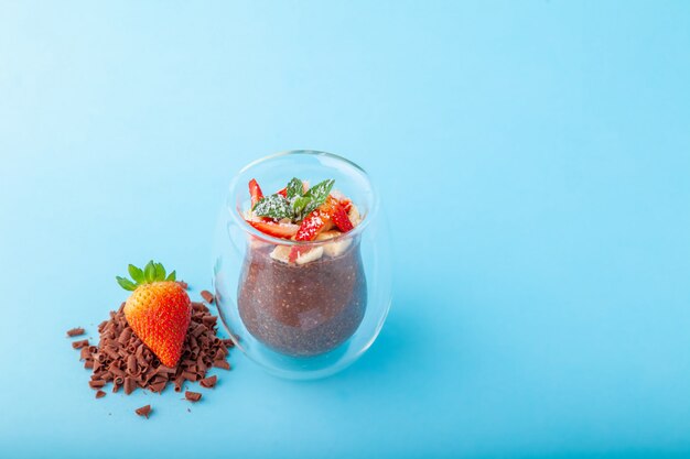 Schokoladen-Chia-Pudding verziert mit Erdbeere auf blauem Hintergrund