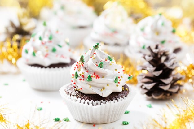 Schokoladen-Cupcake verzierte weiße Sahne- und Tannenbäume. Weihnachtssüßigkeiten.