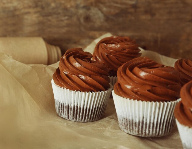 Schokoladen-Cupcakes auf Bäckerpapier über Holzuntergrund