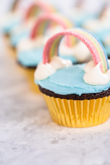 Schokoladen-Cupcakes mit blauem Buttercreme-Zuckerguss und Regenbogen für die Einhorn-Geburtstagsfeier