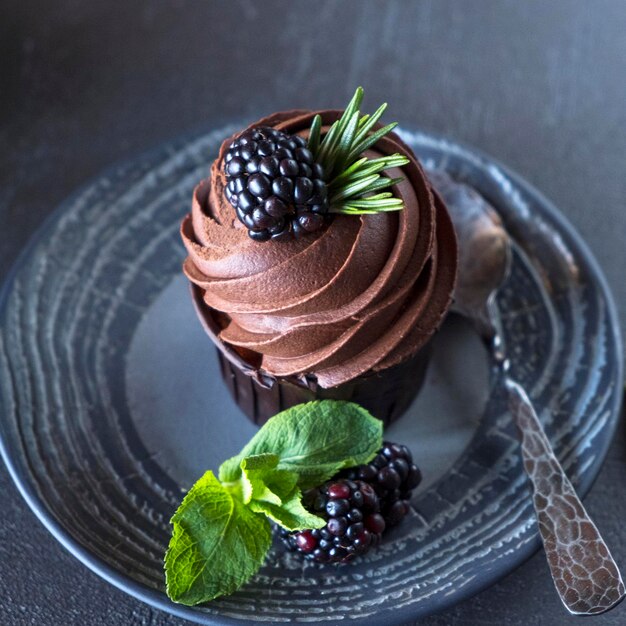 Schokoladen-Cupcakes mit Brombeere und Minze Leckere Schokoladen-Cupcakes in einem Teller