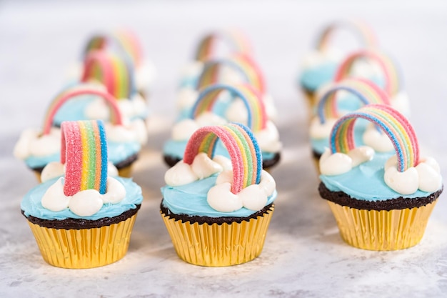 Schokoladen-Cupcakes verziert mit blauem Buttercreme-Zuckerguss und Regenbogen für eine Geburtstagsparty mit Einhorn-Thema.