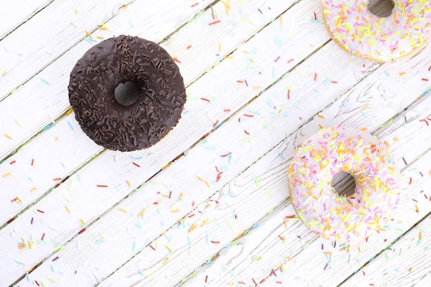 Schokoladen-Donut auf weißem Holzhintergrund und einer Streuung von süßen Ornamenten