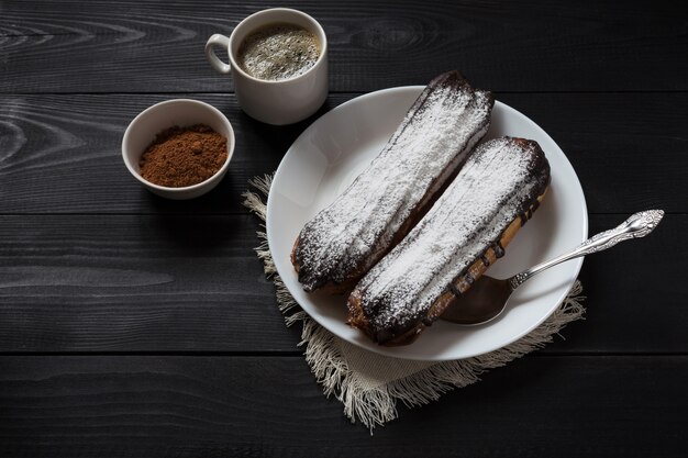 Schokoladen Eclairs auf einem dunklen hölzernen Hintergrund