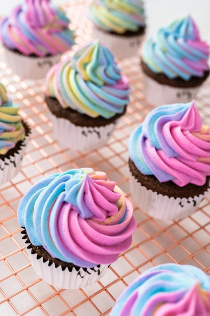 Schokoladen-Einhorn-Cupcakes mit bunter Buttercreme-Glasur und Streuseln dekorieren.