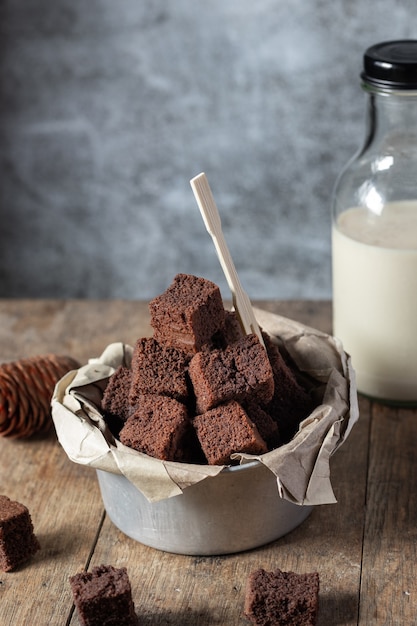 Schokoladen-Mini-Brownie-Kuchen, Dessert mit Milch auf dunklem Hintergrund auf einem Holztisch.