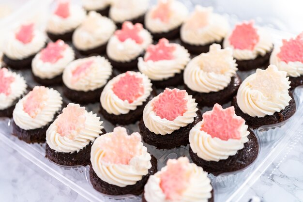 Schokoladen-Mini-Cupcakes mit italienischem Buttercreme-Zuckerguss, verziert mit glitzernden Schokoladen-Schneeflocken.