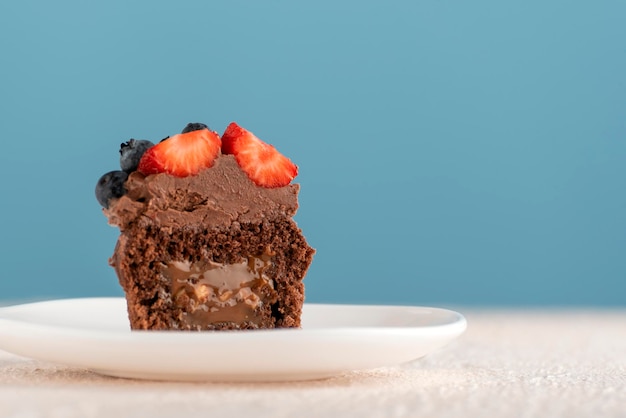 Schokoladen-Muffin mit Karamellfüllung und Beeren Schokoladen-Cupcake mit dunkler Schokoladenglasur auf blauem Hintergrund