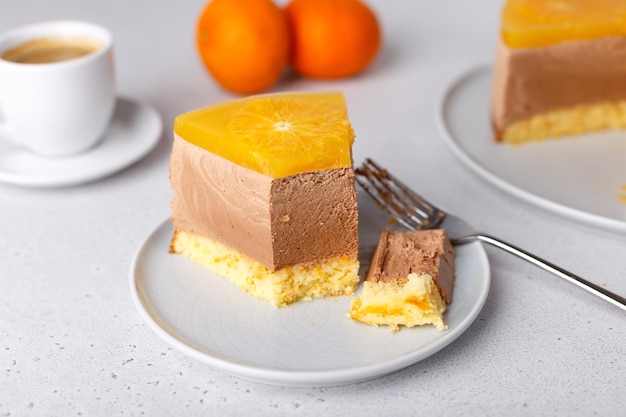 Schokoladen-Orangen-Mousse-Kuchen mit Gelee auf Keksbasis und Orangenkreisen Stück hausgemachter Käsekuchen und eine Tasse Kaffee Traditionelles Feiertagsdessert Selektiver Fokus in der Nähe