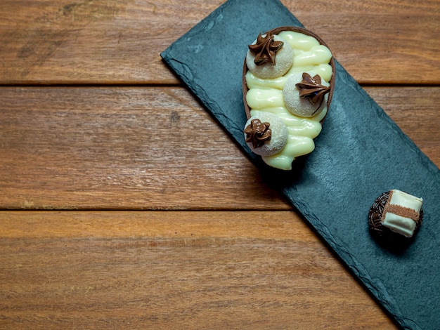 Schokoladen-Osterei und Schokoladentrüffel auf schwarzem Stein mit Holzhintergrund