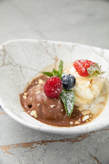 Schokoladen-Vanilleeis mit Beeren auf einem grauen Tisch