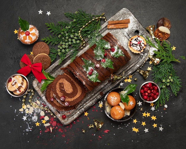 Schokoladen-Weihnachtsscheit auf dunklem Hintergrund, traditionelles Dessert der Weihnachtszeit, Ansicht von oben