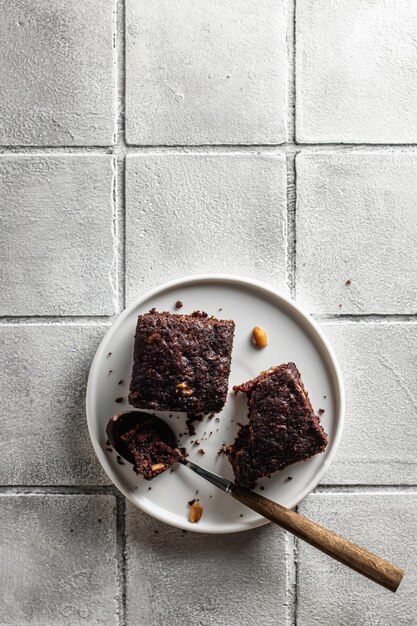 Schokoladen-Zucchini-Brownie auf einer weißen Platte auf einem grauen Fliesenhintergrund