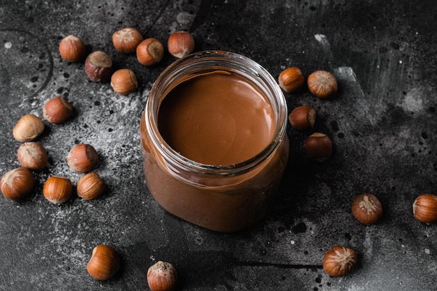 Foto schokoladenaufstrich oder nougatcreme mit haselnuss auf schwarzem, dunklem steintischhintergrund