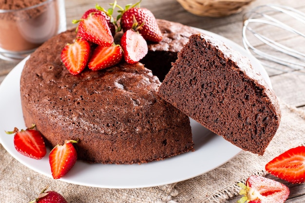 Schokoladenbiskuitkuchen mit Erdbeeren auf einem Holztisch