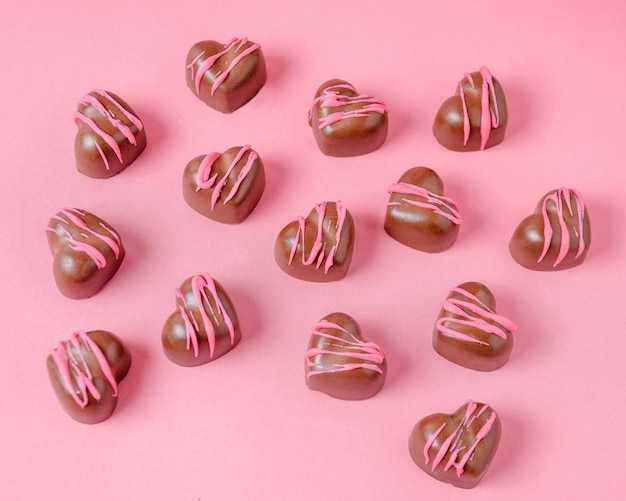 Schokoladenbonbons in Form von Herzen mit rosa Zuckerglasur Rosa einfarbiger Hintergrund